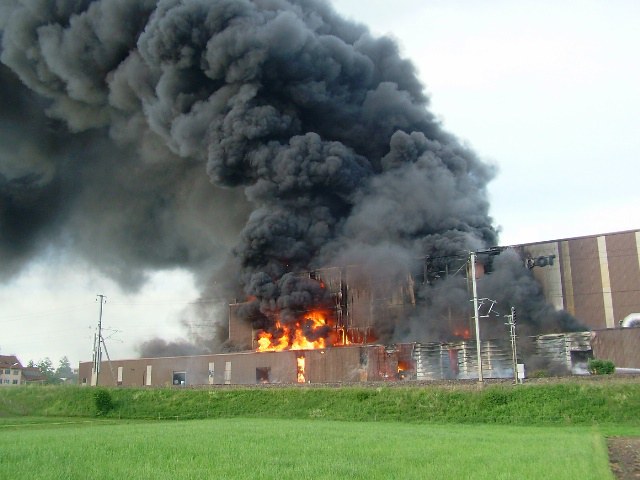 Brennendes Gewerbegebäude mit schwarze Rauchfahne