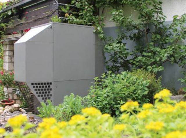 Wärmepumpe in einem Garten mit gelben Blumen