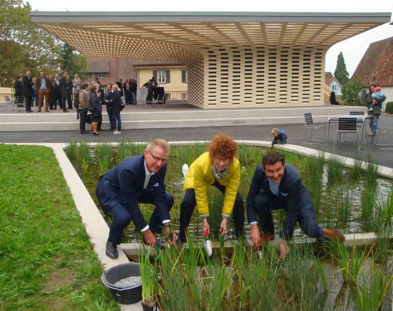 Baudirektor Heinz Tännler, Landschaftsarchitektin Marceline Hauri und Stadtrat André Wicki (vlnr.) setzen zur Eröffnung des neuen Stadtgartens Zug die letzten Schwertlilien in den Stadtgarten-Teich. 