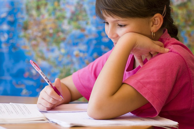 girl with a pen in one hand, holding her head with the other hand