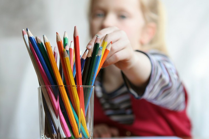 Ein Mädchen greift nach einem Farbstift