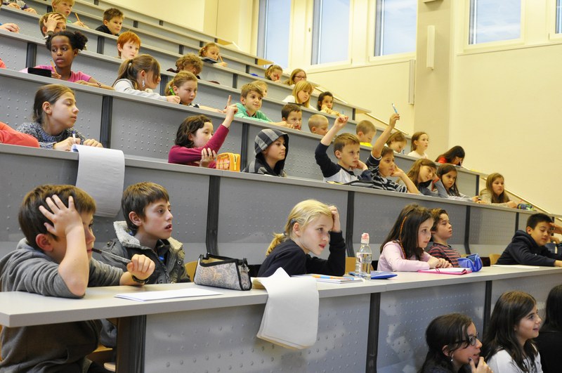 Kinder lauschen im Hörsaal gespannt der Vorlesung