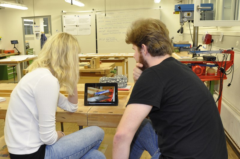Studierende schauen sich im Werkraum Video-Tutorials an