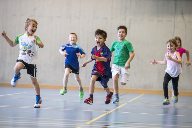 Kinder springen in der Turnhalle herum.