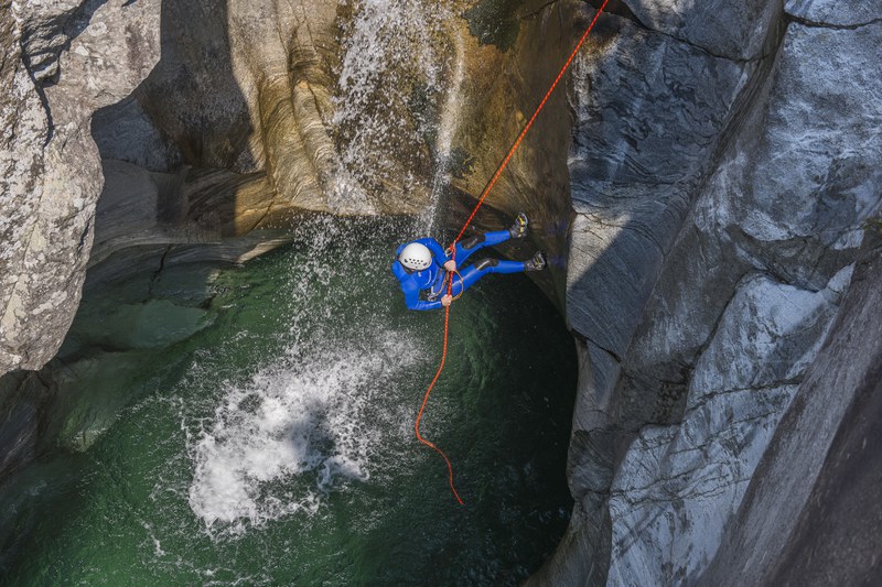 Ein Mensch seilt sich in einen Canyon ab.